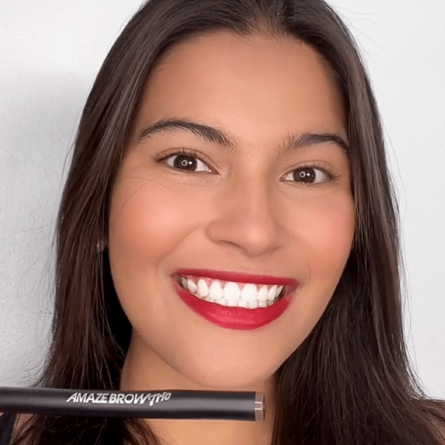 Smiling woman holding Amaze Brow growth serum 3-tip eyebrow pen